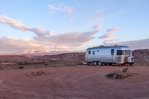 Grey RV under blue and white sky.